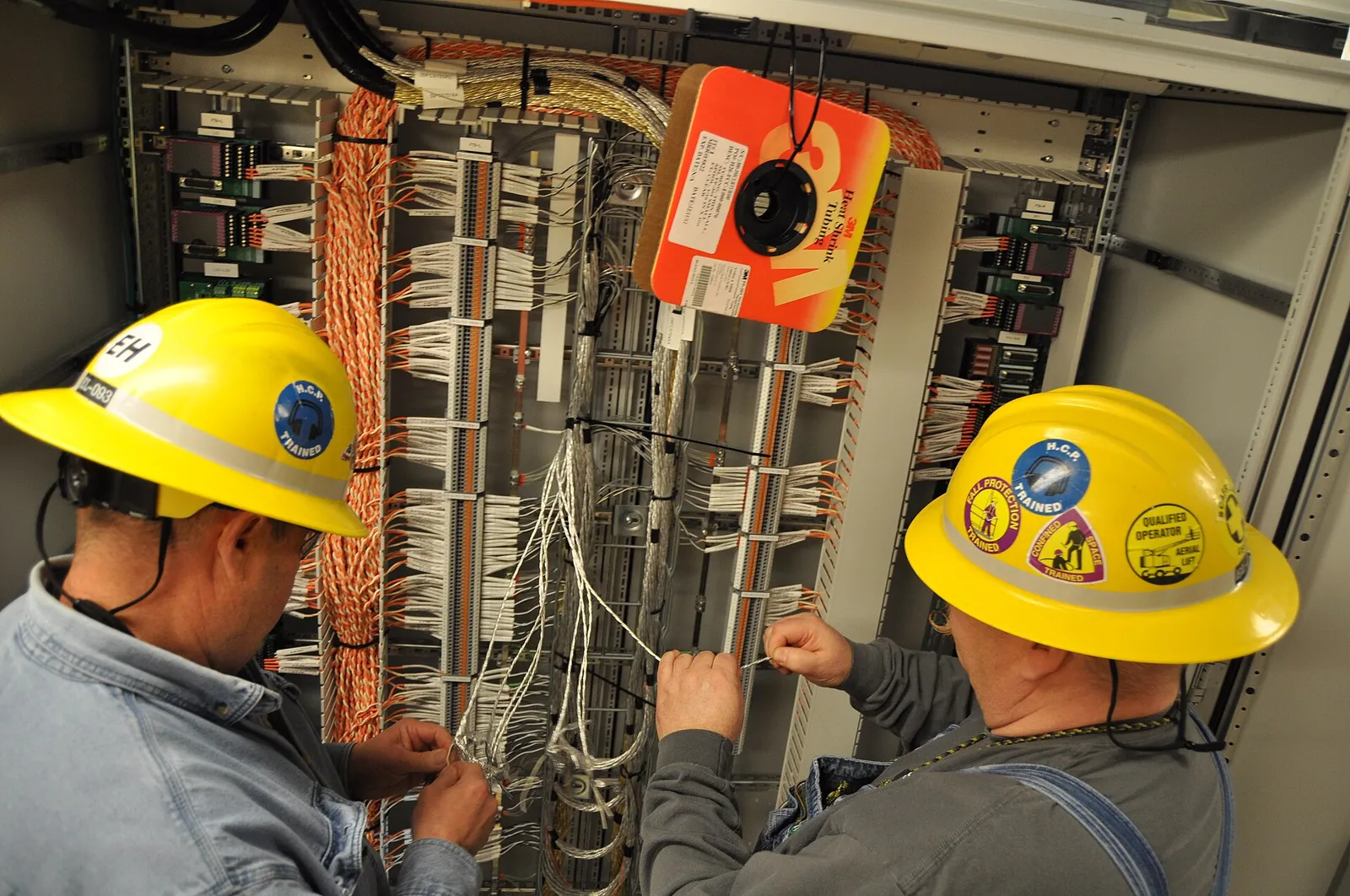 Electricians wiring an industrial control cabinet