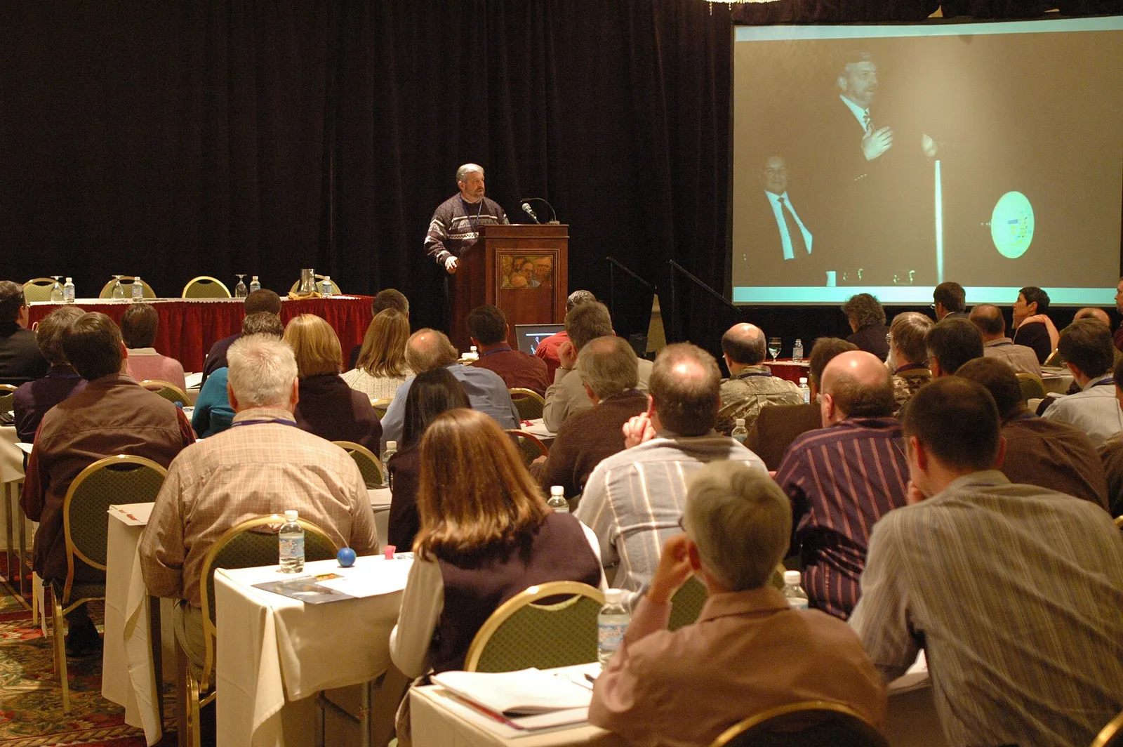 Conference audience at round tables facing a speaker