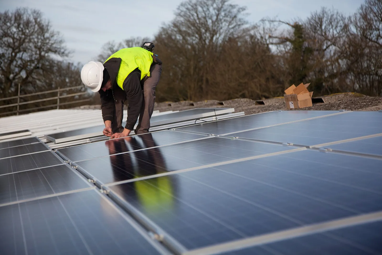 Worker in hard hat installing rooftop solar panels